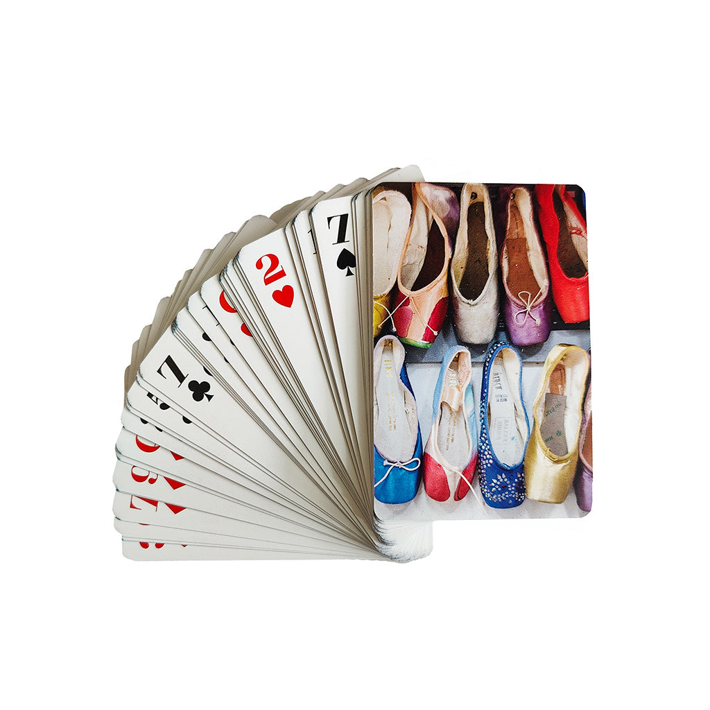 A fanned deck of playing cards on a plain white background, with the top card showing a photograph of colourful ballet pointe shoes.