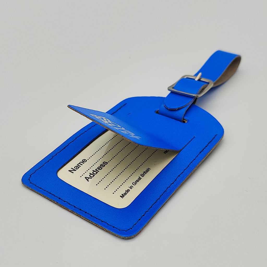 Blue back of the luggage tag with text Royal Ballet London and address label on a gray background