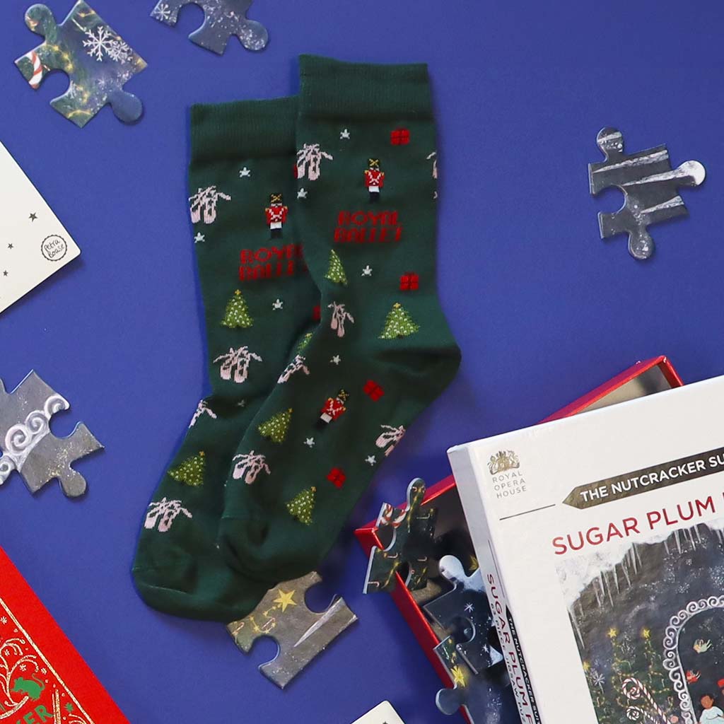 Pair of green Nutcracker ballet socks with festive designs on a white background