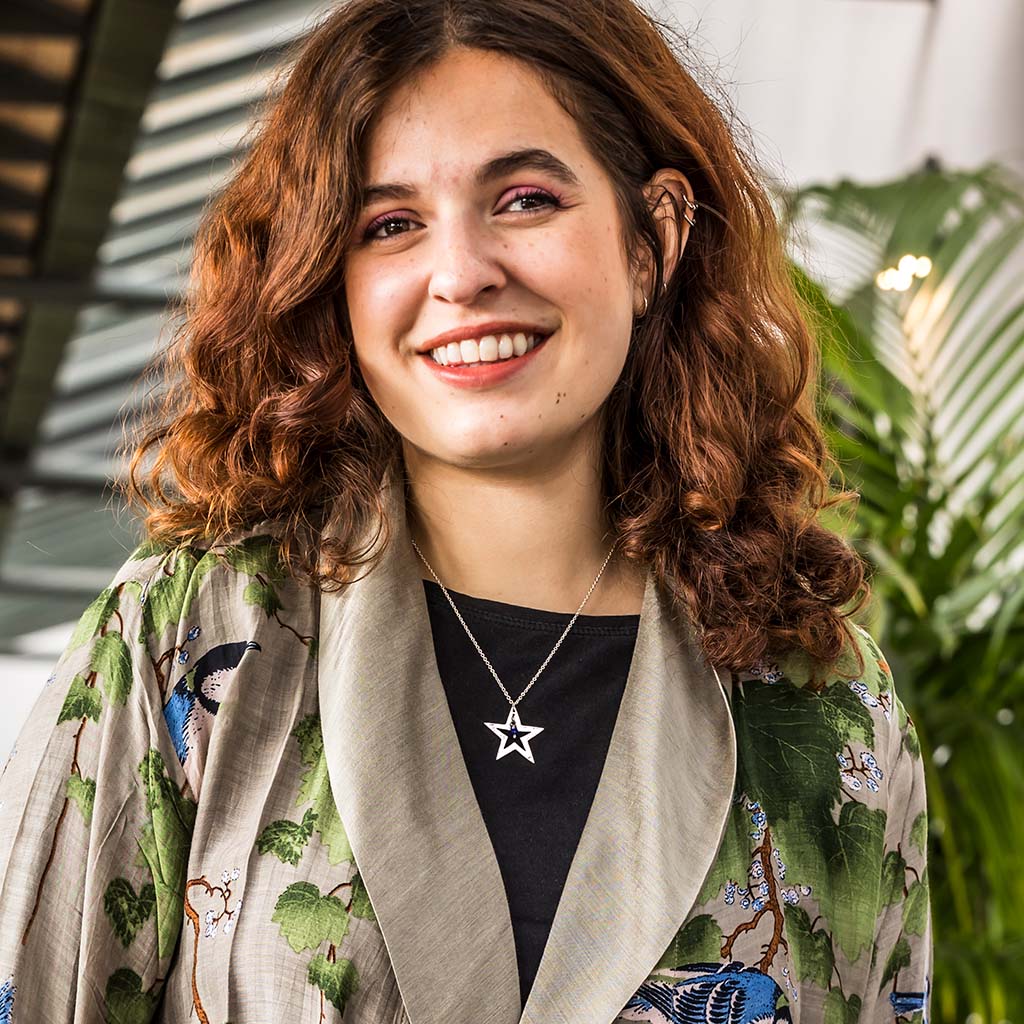 Model wears Nutcracker Star Necklace on terrace in front of plants