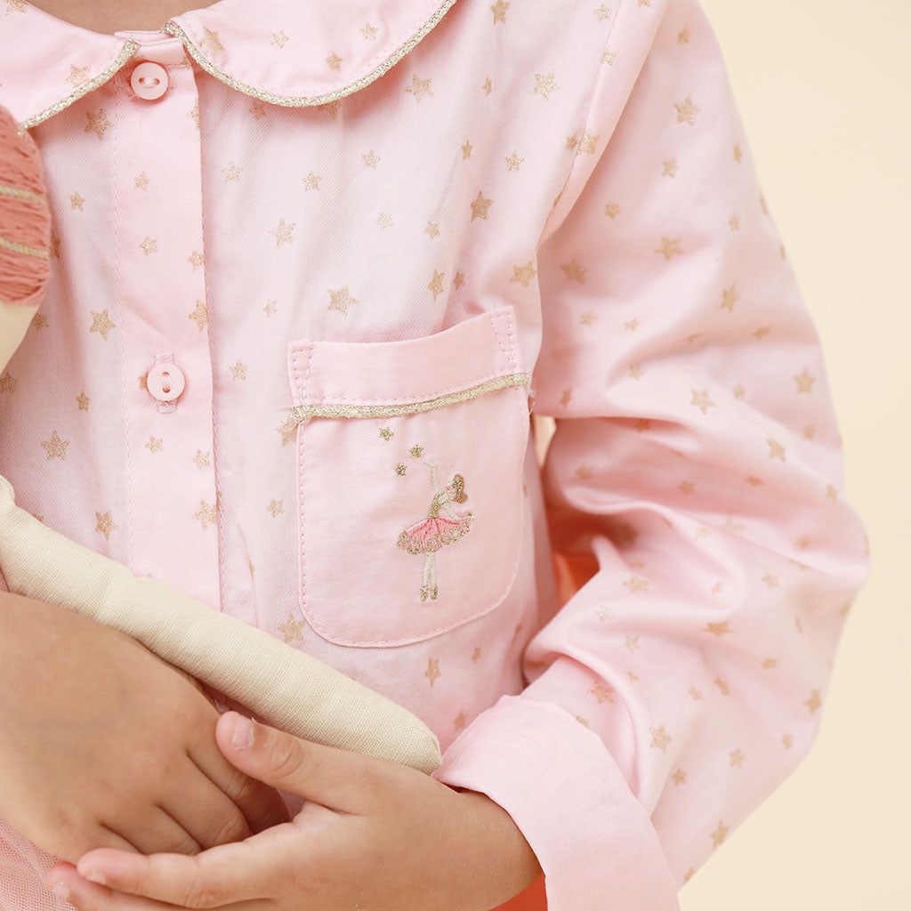 Close-up of a child wearing a pink star ballerina pajama set on a yellow background