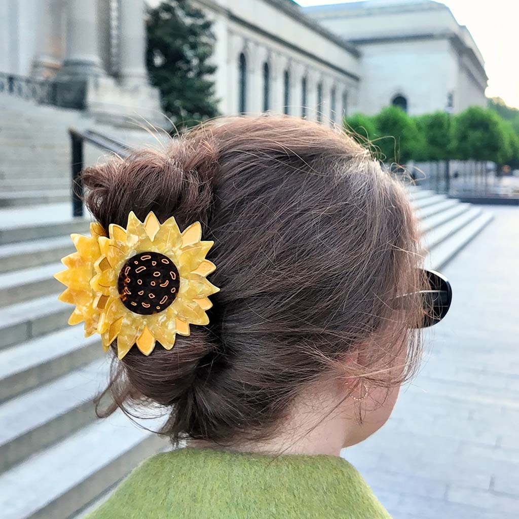 Yellow sunflower-shaped hair clip on a white background