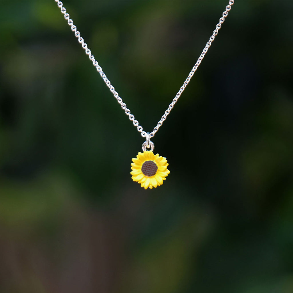 Sunflower pendant necklace on a blurred green background