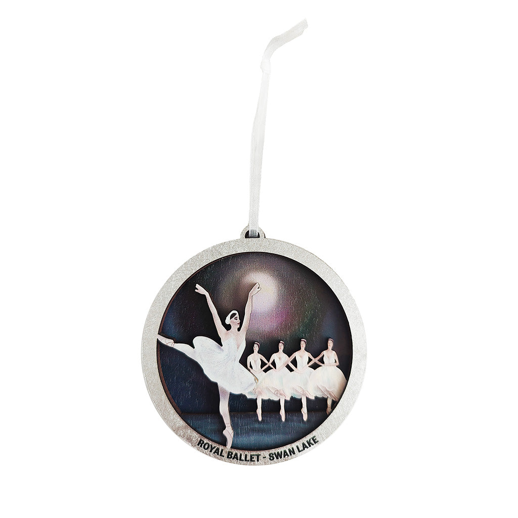 wooden christmas decoration with ballet dancers in white dressed from Swan Lake with a dark background and silver rim hanging on a silver ribbon on a white background