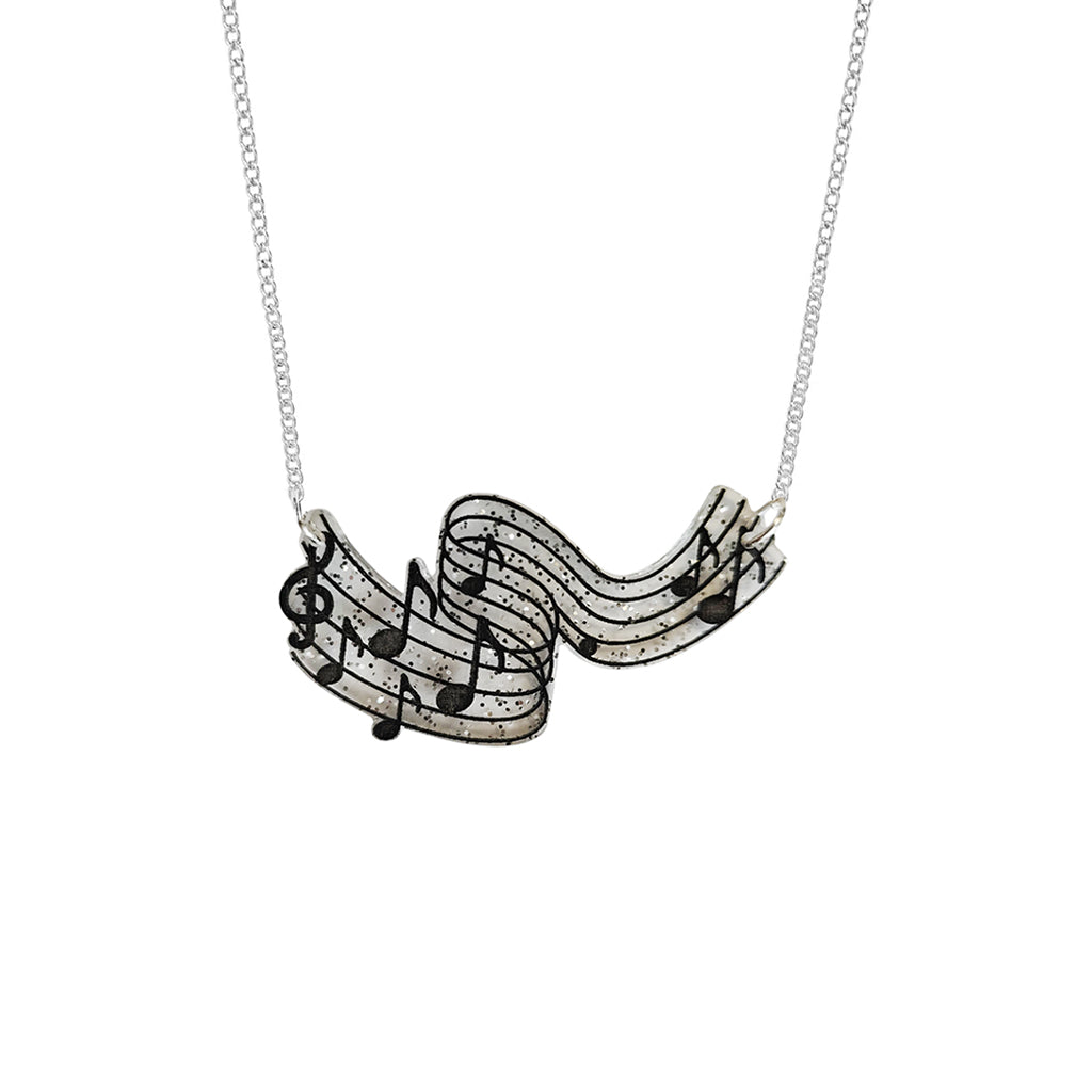 A silver necklace featuring a wavy musical staff pendant with black musical notes, shown against a plain white background.