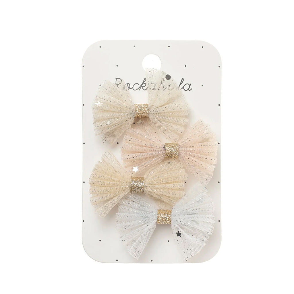 A set of four tulle hair bows in soft pastel shades of cream, beige, blush pink, and white, each with a glittery gold centre band, displayed on a white card with the brand name 'Rockahula'.