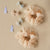 A Sparkly Tulle Scrunchie made from beige tulle fabric with star patterns on a white background.