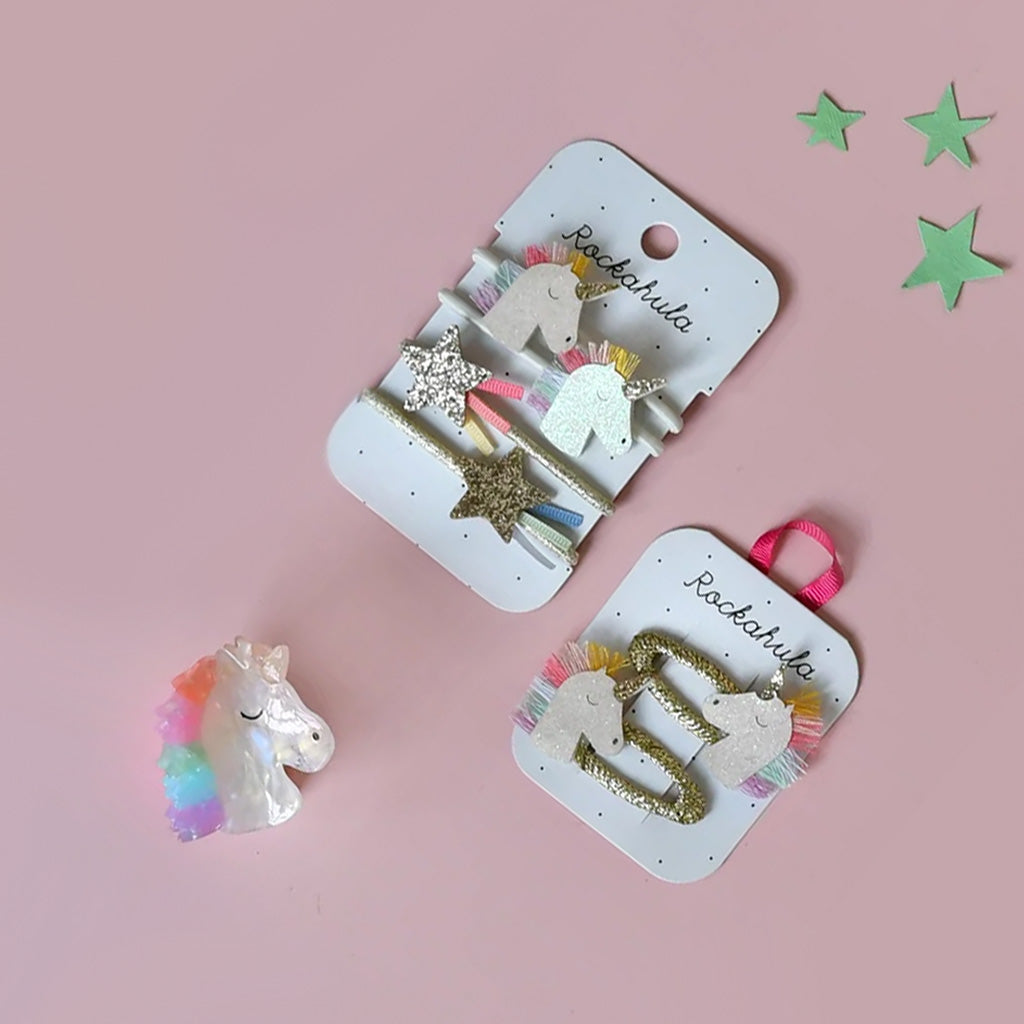 Unicorn-shaped hair clips on display cards with a pink background