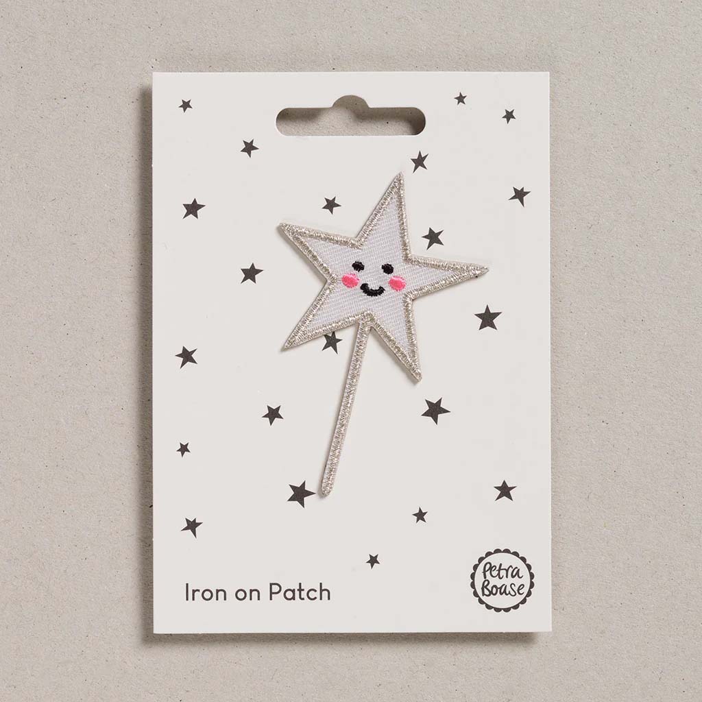 Star-shaped iron on patch with a smiling face on a white card with star patterns, branded &#39;Petra Boase&#39;.