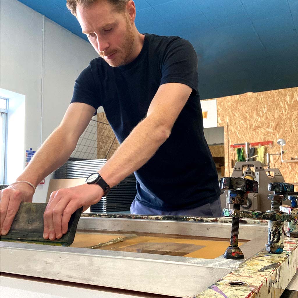 Artist Will Clarke working with screen printing equipment in a workshop setting