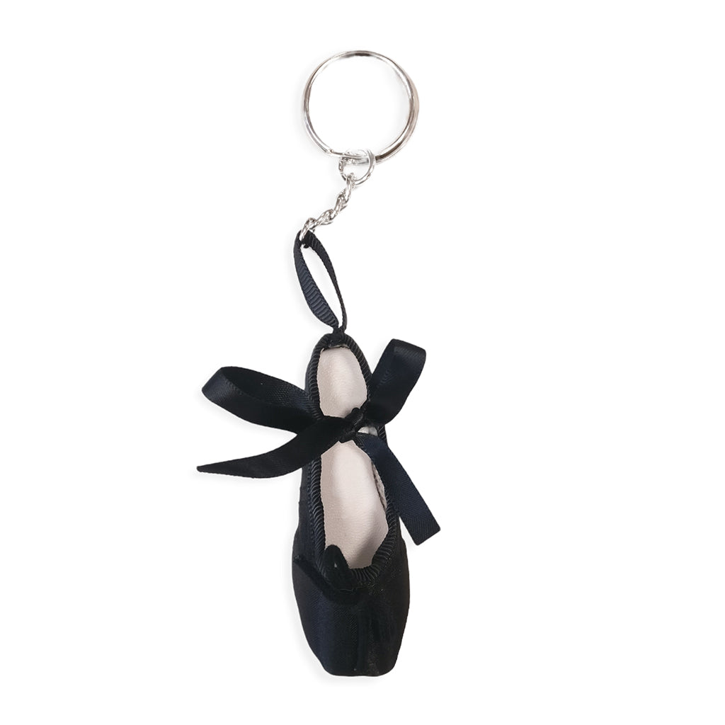 A black keyring in the shape of a ballet shoe against a white background. The keyring is hanging vertically, suspended by a short metal chain with a larger ring at the top for attaching to keys. There are two black bows, a larger one about two thirds of the way up the shoe, and a smaller one at the bottom. 